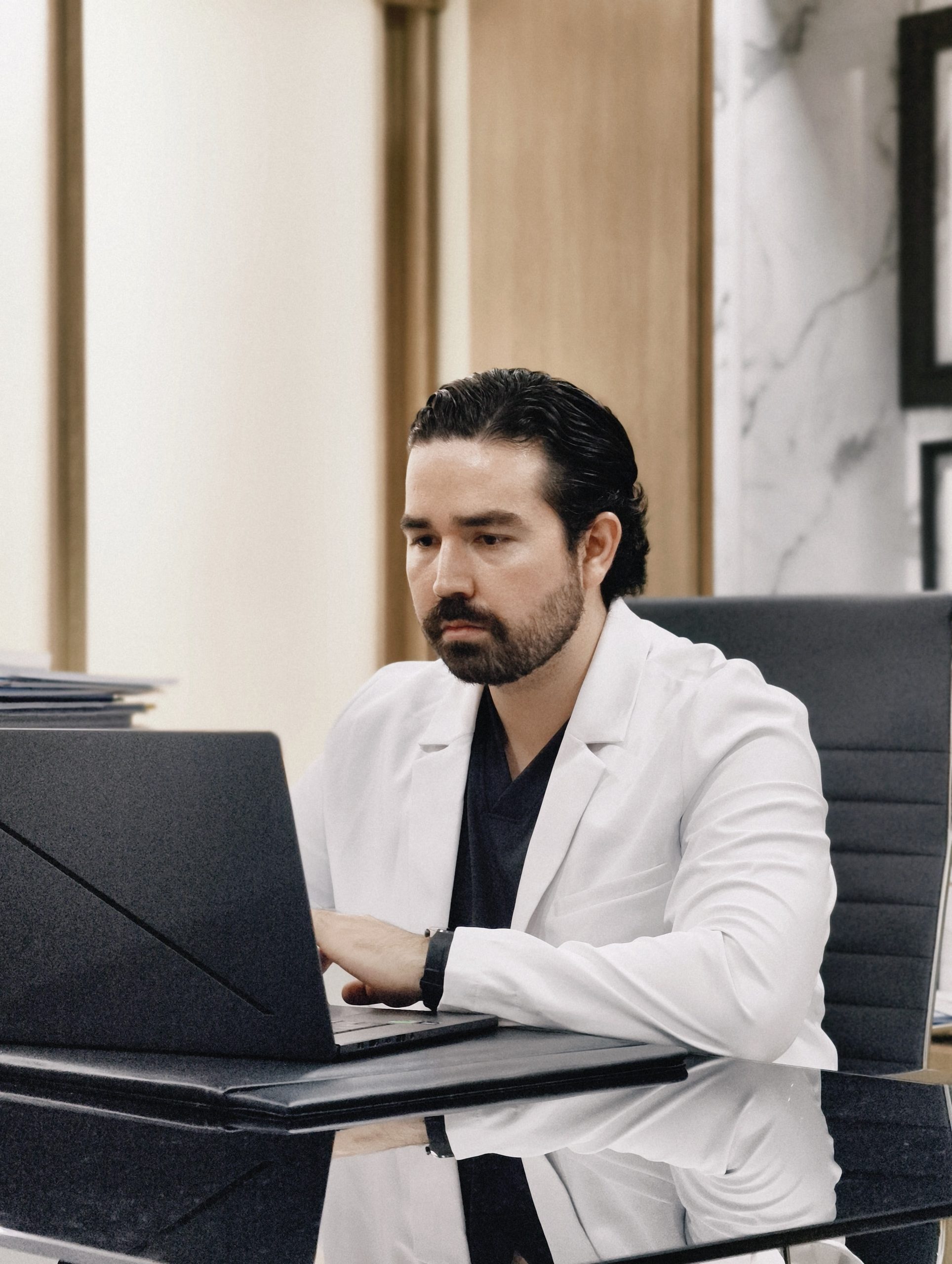 Dr. Braulio Ayala trabajando en su laptop en su consultorio de Doctors Hospital, Monterrey