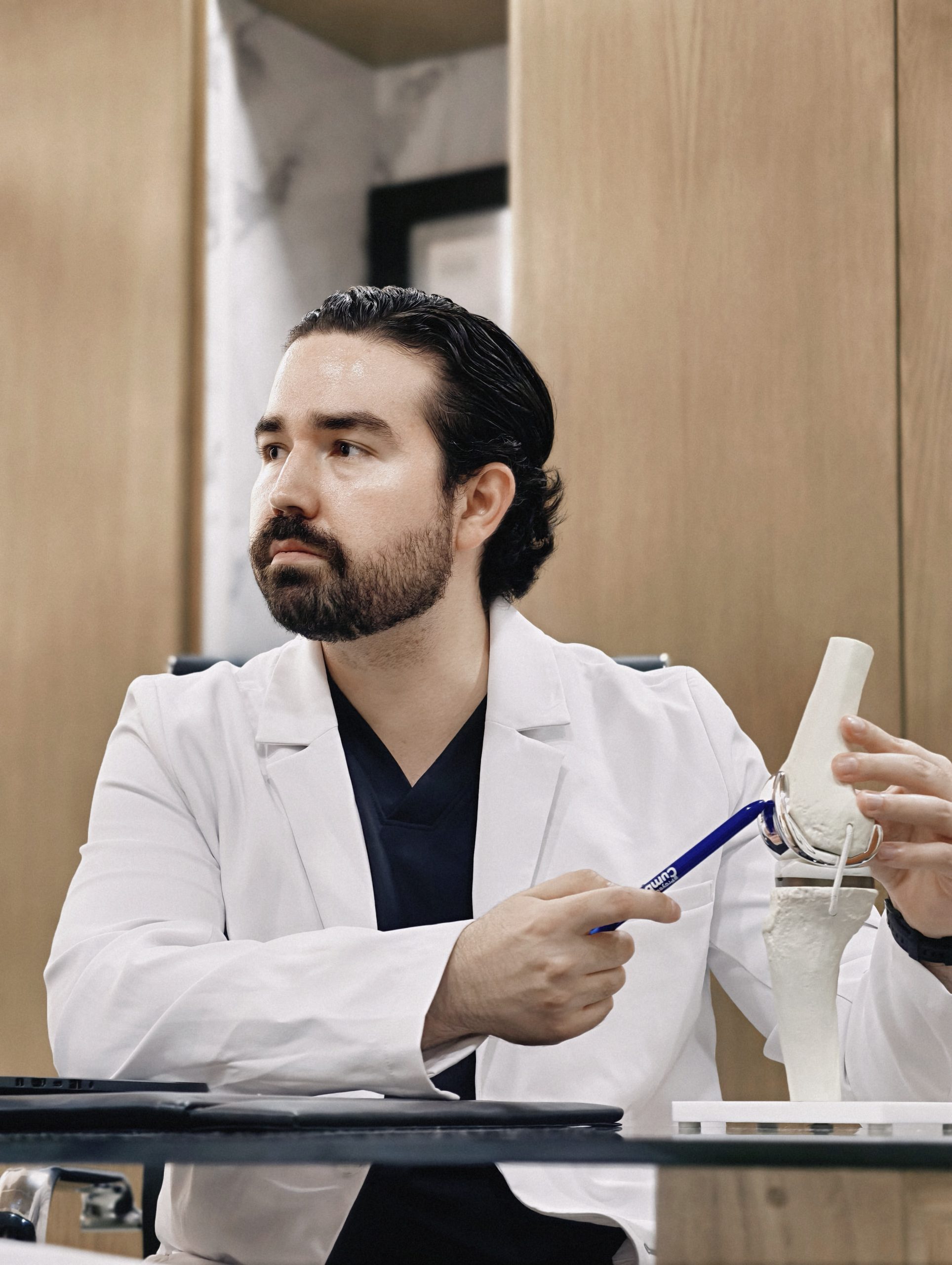 Dr. Braulio Ayala señalando con un puntero un modelo de implante de rodilla durante una explicación clínica